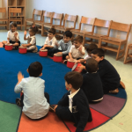Children playing drums in a classroom circle.