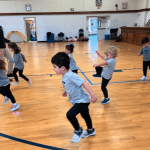 Children running in a gym during activity.